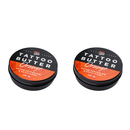 Two tins of Love Ink Tattoo Butter on a transparent background. Both tins are labeled 'Orange' with an orange design.