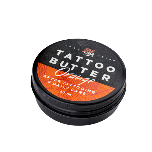 Close-up of a 50ml jar of Tattoo Butter Orange by LoveInk. The product features a black and orange design, emphasizing its use for after tattooing and daily care.